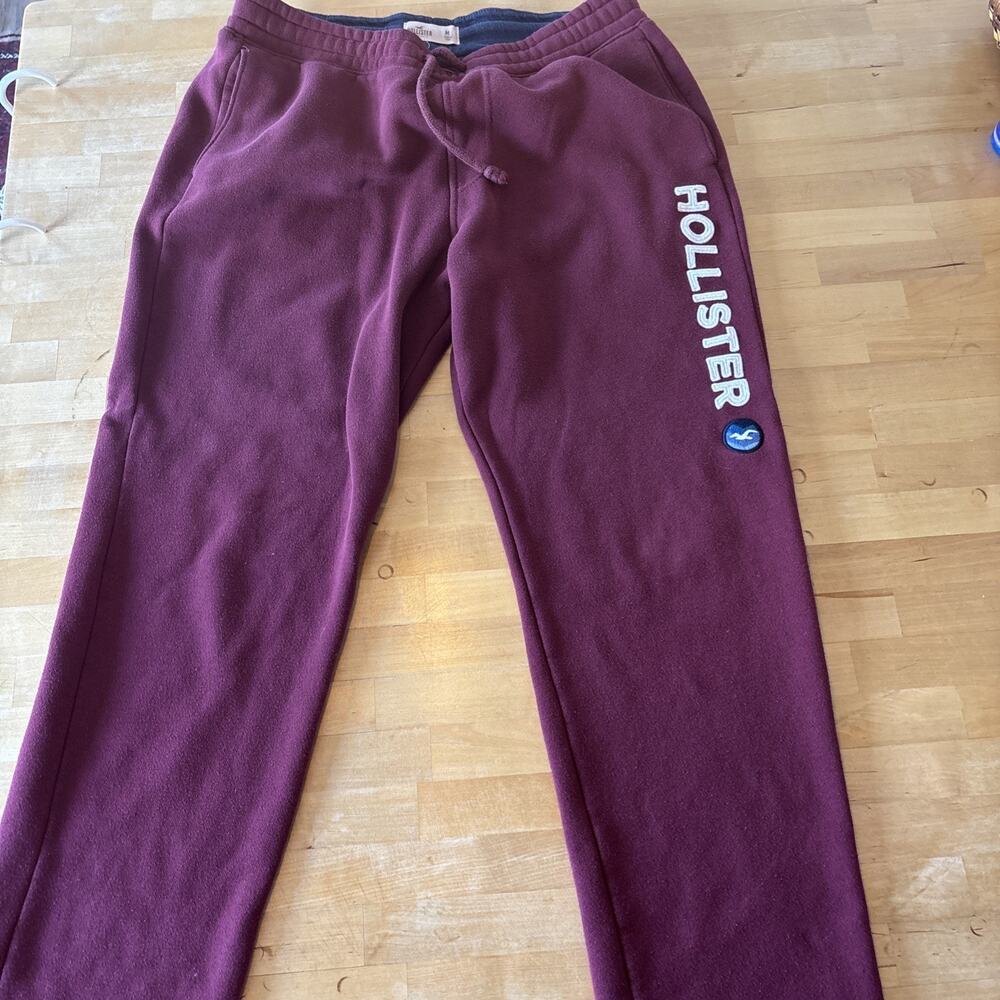 Medium burgundy Hollister sweatpants feature a vertical white logo graphic